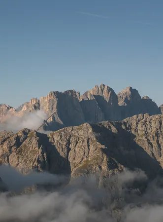 UNESCO World Heritage Dolomites: panorama of the Geisler peaks in Puez-Geisler Nature Park at sunrise with fog banks