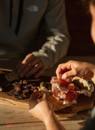 Traditional South Tyrolean snack with speck, cheese and red wine on wooden board in cozy alpine hut near Villnöß