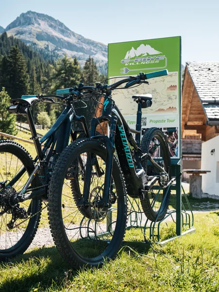 E-Bike Villnöß charging station with Specialized e-bikes in front of traditional alpine hut with Peitlerkofel view