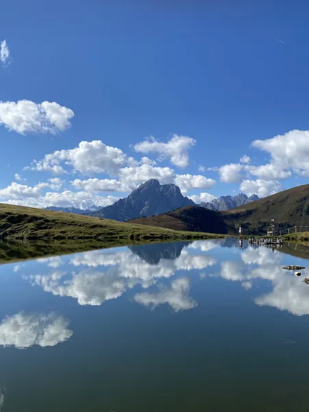 Mountain lake on Luson Alp with perfect reflection of Geisler Dolomites under brilliant blue sky in Villnöß South Tyrol