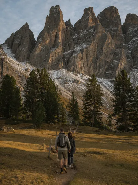 Female hiker on alpine meadow of Geisler Alm with majestic view of the Geisler peaks in summer green