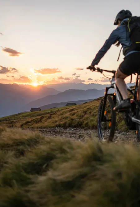 Radfahrer auf der Lüsner Alm mit Panoramablick auf die Dolomitengipfel im Hintergrund