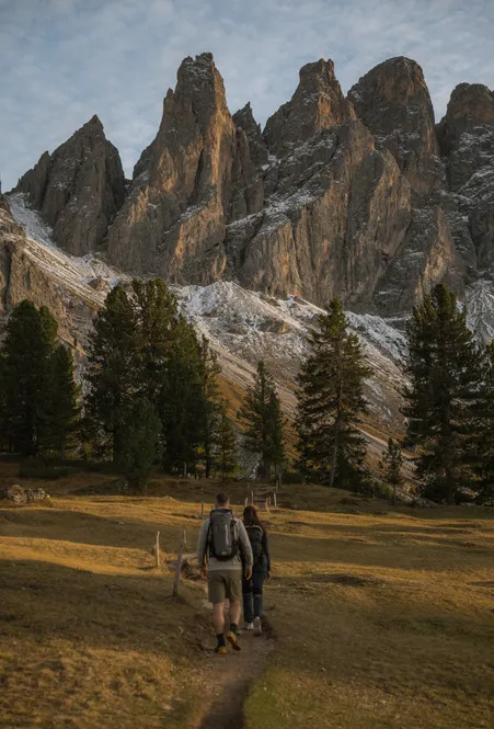 Wanderin auf Almwiese der Geisleralm mit majestätischem Blick auf die Geislerspitzen im Sommergrün