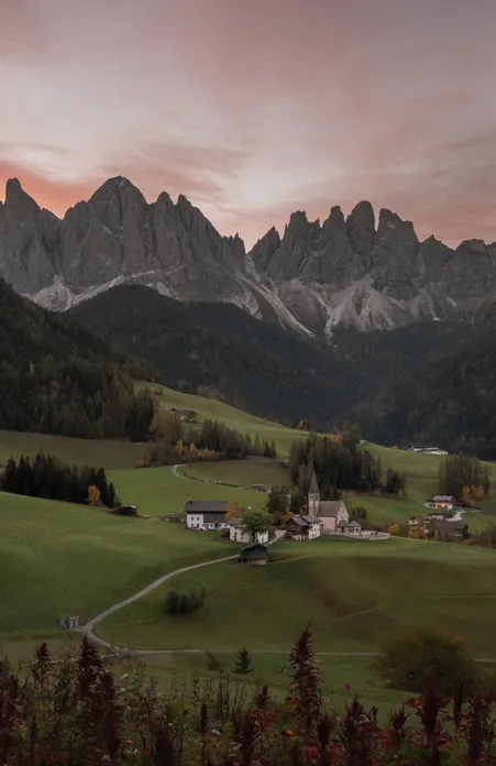 St. Magdalena in Villnöß bei Sonnenuntergang mit den Geisler-Spitzen der Dolomiten und herbstlichen Almwiesen