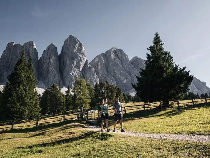 Zwei Wanderer auf einem Almweg unterhalb der Geisler-Gruppe im Villnösser Naturpark Puez-Geisler, Südtiroler Dolomiten